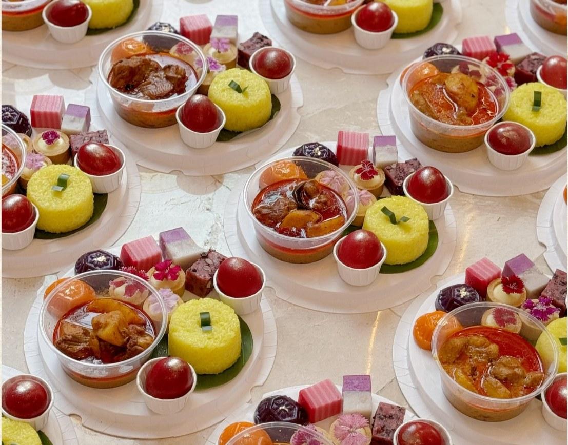 Cherry Blossom Gift Set arranged with angku kuih, bite size kuih, lemon white chocolate tarts, curry chicken, nasi pulut kunyit and red eggs in round packaging.